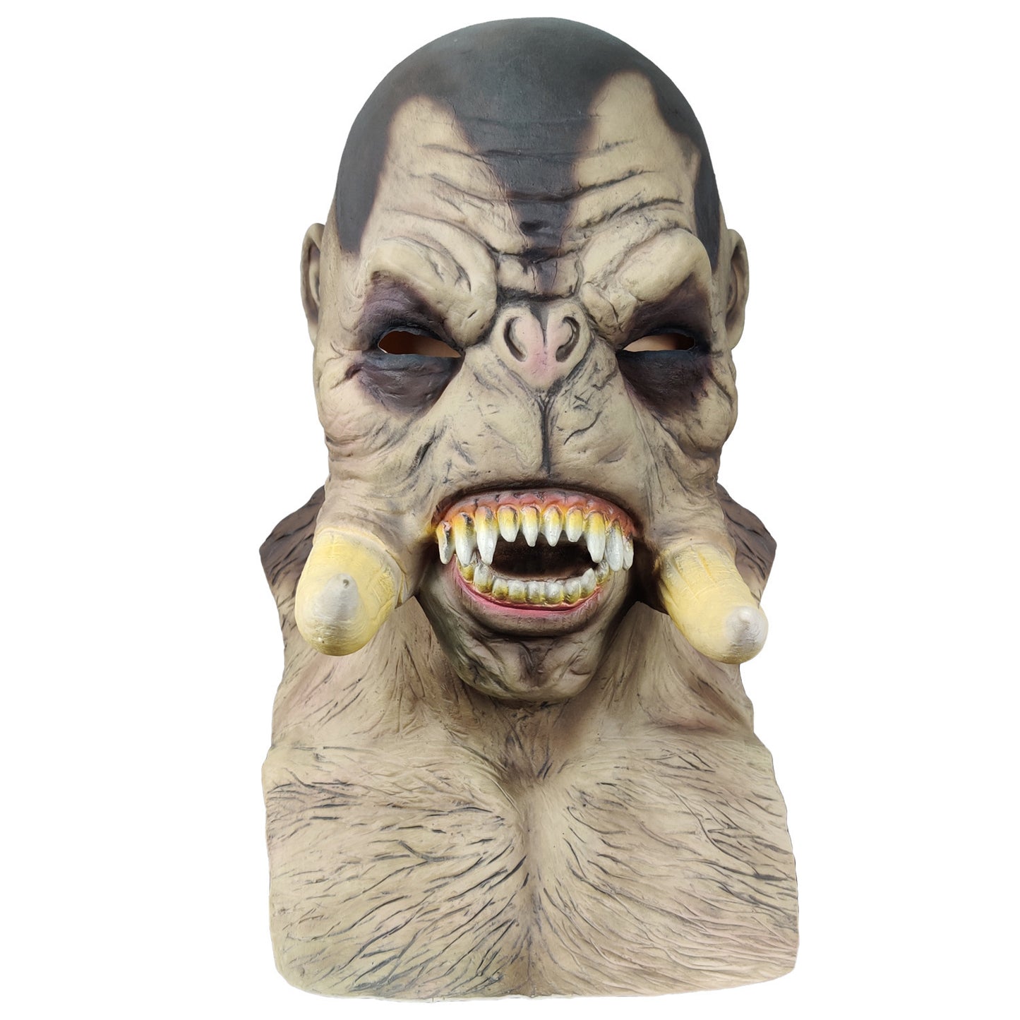 Grotesque mask of a monster with bulging eyes, sharp yellowed teeth, and elongated tusks protruding from its cheeks, featuring weathered skin tones and dark markings.
