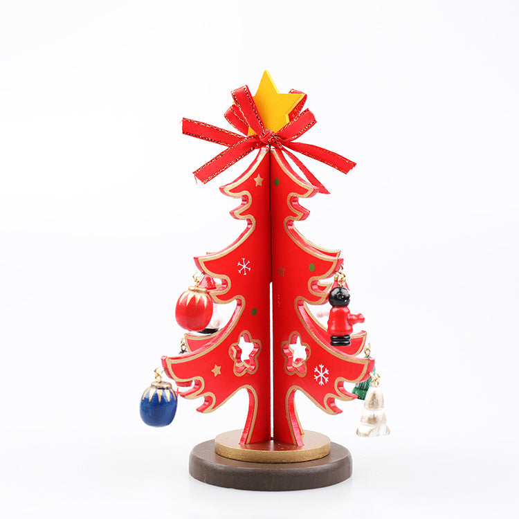 A small, decorative red Christmas tree with a red bow and star on top. It features ornaments in various colors, including red, blue, and white, on a wooden base.