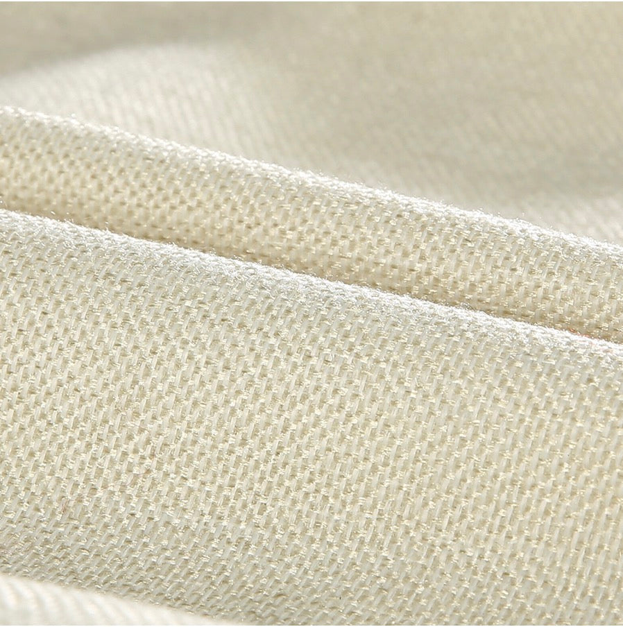 Close-up of cream-colored textured fabric with a woven pattern, showcasing its intricate and detailed weave.