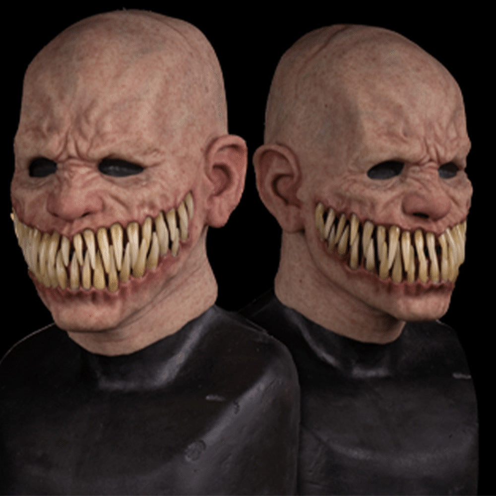 Two creepy figures with bald heads, hollow eyes, and wide grins reveal sharp, jagged teeth. Their expressions are unsettling, and they are dressed in dark clothing against a black background.