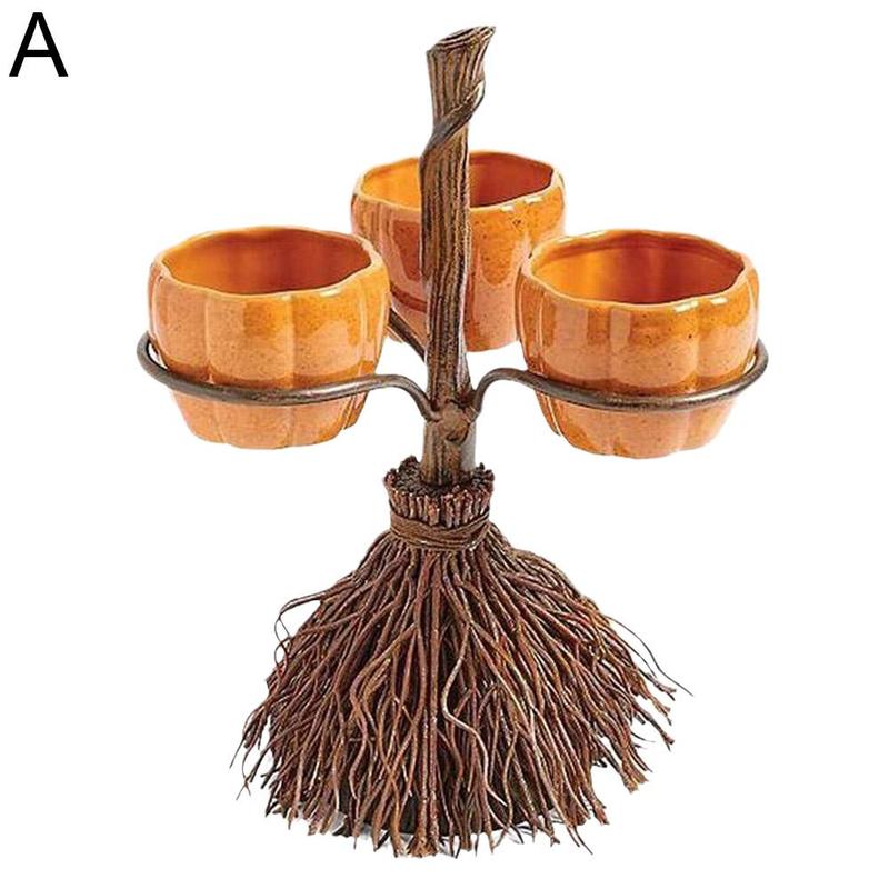 A decorative stand with a rustic broom base holds three small pumpkin-shaped holders, arranged on metal rings attached to a branch-like stem.