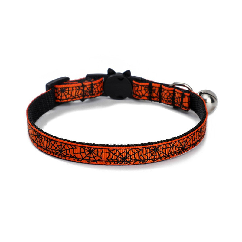 Orange and black cat collar with spiderweb pattern, featuring a breakaway buckle and a small silver bell attached.