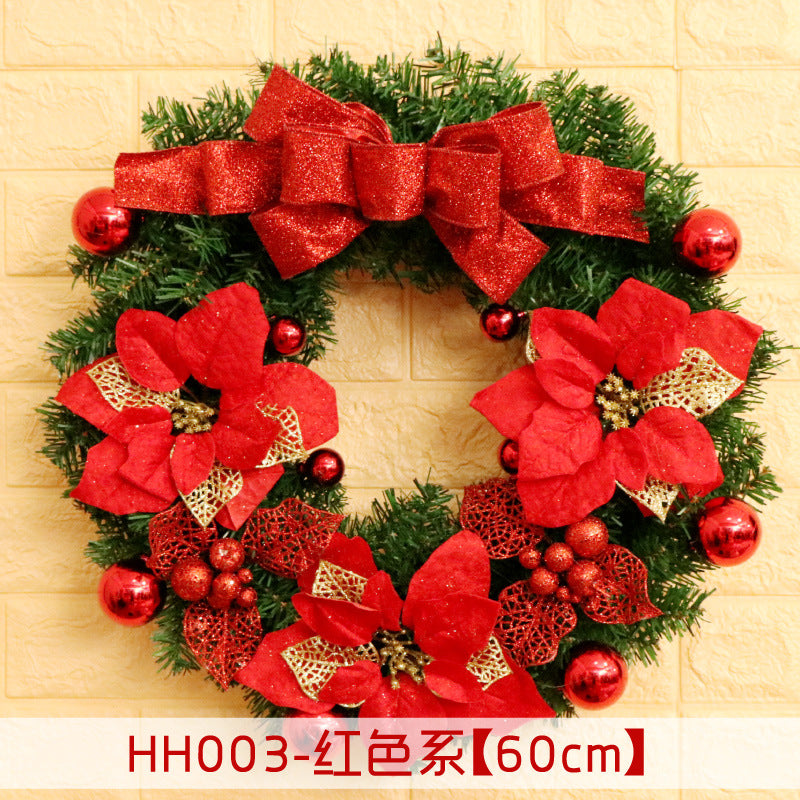 Festive wreath with red poinsettias, glittery gold accents, red berries, and a large red bow, set against a light brick wall. Text indicates dimension as 60cm.