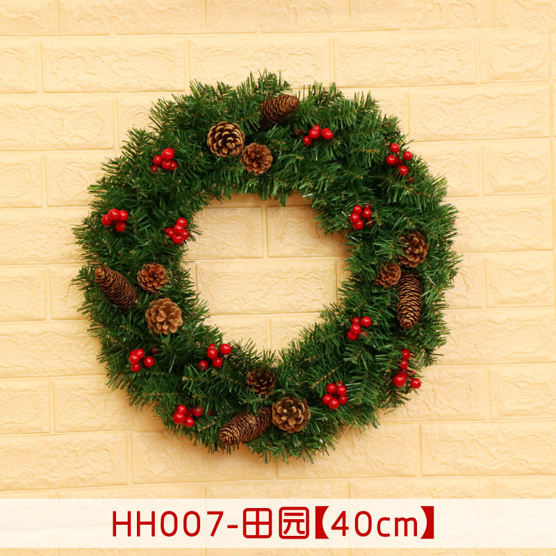 Festive green wreath with pinecones and red berries, measuring 40 cm in diameter, hanging on a light brick wall.