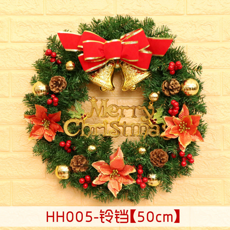 A festive Christmas wreath with red flowers, gold ornaments, pine cones, and red berries. Two gold bells and a red bow sit atop, with a "Merry Christmas" sign in the center.