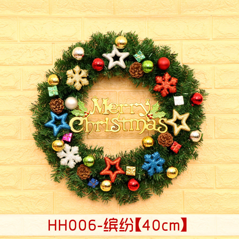 Festive Christmas wreath with "Merry Christmas" text, adorned with colorful stars, snowflakes, ornaments, and pinecones, set against a yellow brick wall.