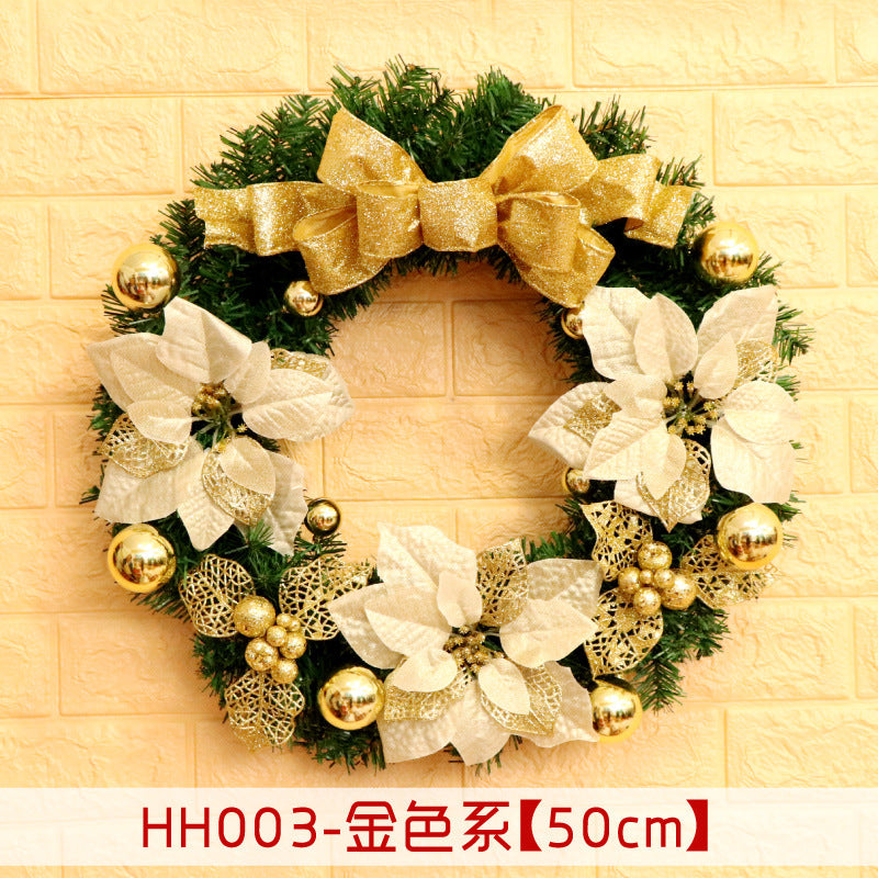 A festive wreath with golden bows, white poinsettias, and gold ornaments on a green base. It's displayed against a light brick wall. Dimensions are labeled 50cm.