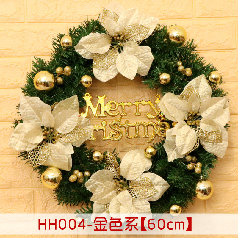 Festive Christmas wreath with gold poinsettias and baubles, featuring a "Merry Christmas" sign, hanging on a light-colored brick wall.
