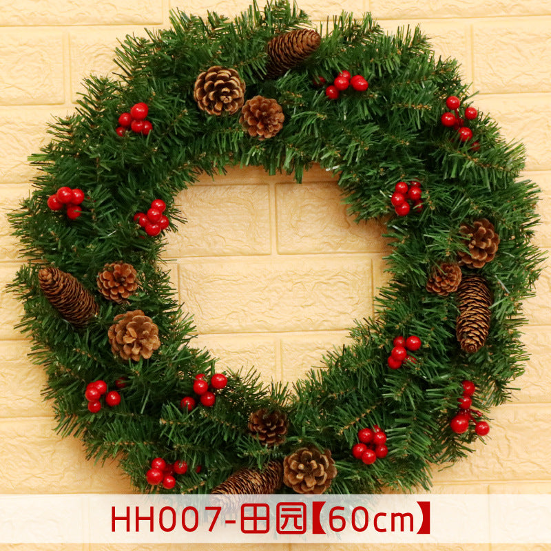 Festive Christmas wreath with green pine needles, red berries, and pinecones, displayed on a light brick wall. Text at the bottom shows item code and dimensions.