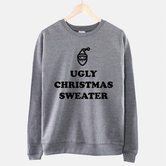 Gray sweatshirt hanging on a wooden hanger with the text "UGLY CHRISTMAS SWEATER" and a simple Santa face design in black on the front.