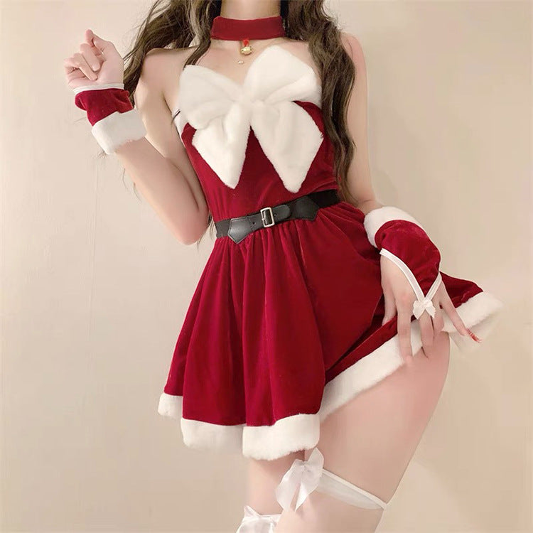 Woman in a festive red dress with white fur trim and a large white bow. She wears matching cuffs and a choker, accented by a black belt, with long wavy hair.