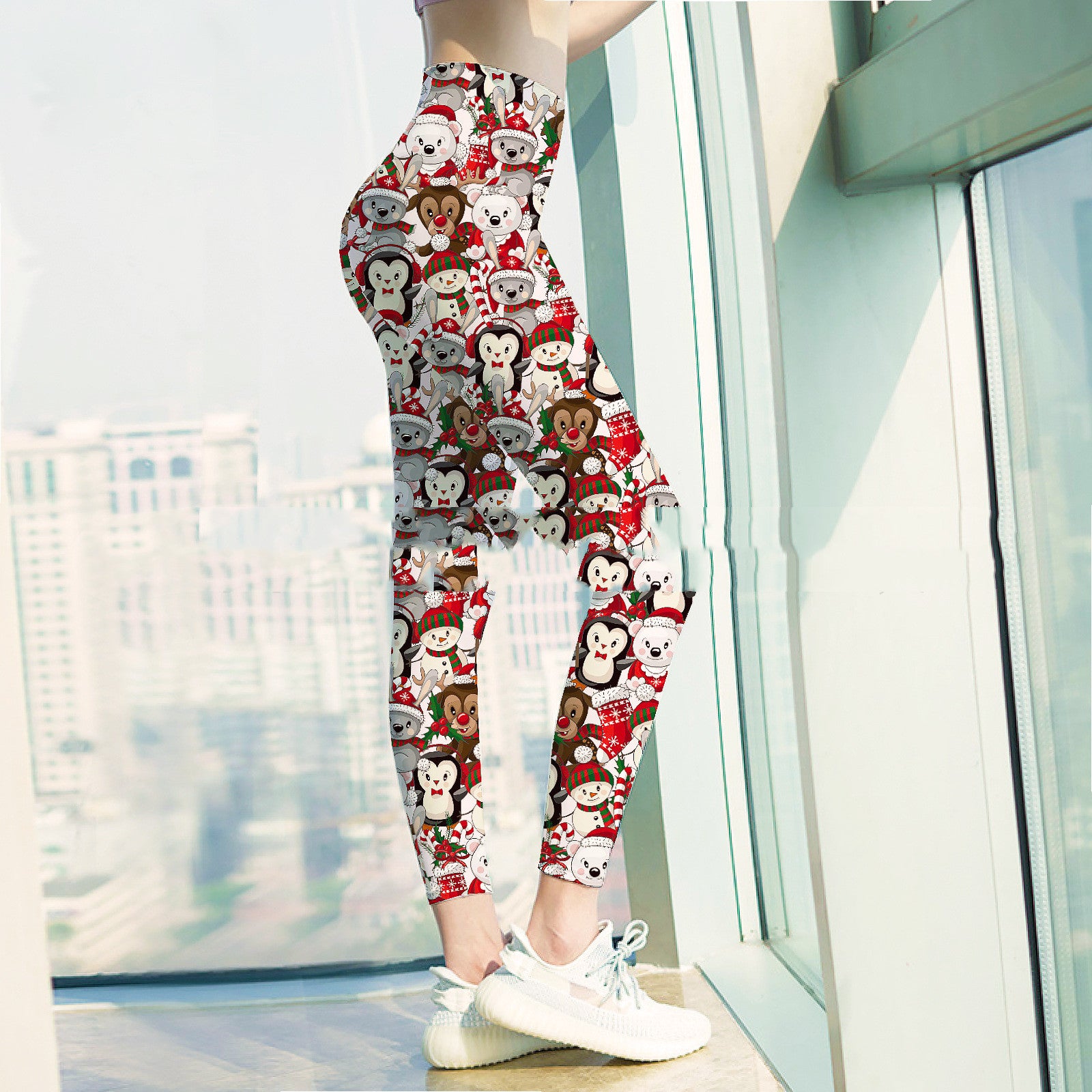 Woman standing by a window in colorful holiday-themed leggings with cartoon animal motifs, and wearing white sneakers. Cityscape visible through the glass.