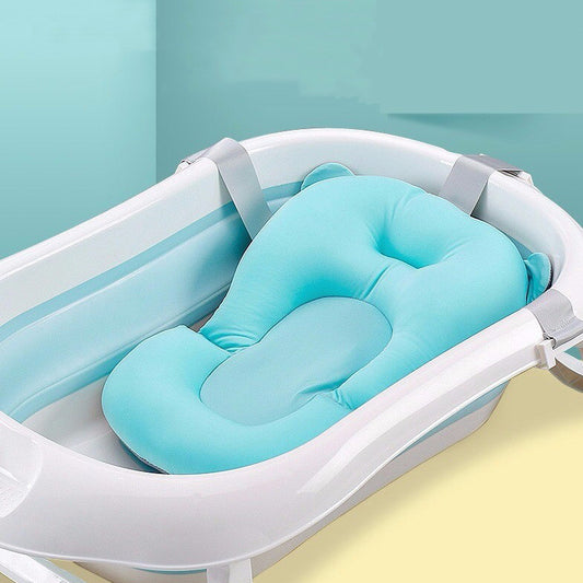A white baby bath with a soft, light blue cushion featuring rounded edges and supportive contours, set against a pastel teal background.