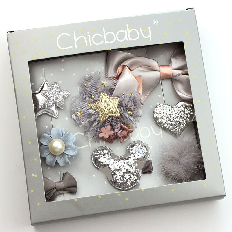 A Chicbaby gift set featuring various hair accessories, including a silver star, a gold star on tulle, sequined heart, and more, in a light gray box with a clear lid.
