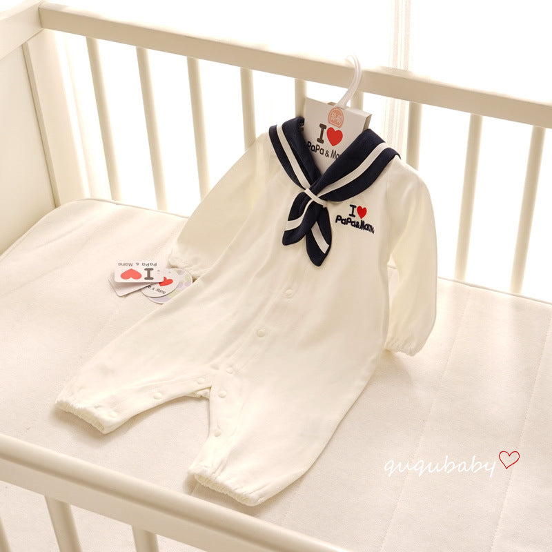 A white baby romper with navy sailor collar and embroidered "I love Papa & Mama" text, hanging in a white crib. Buttons run down the front for easy fastening.