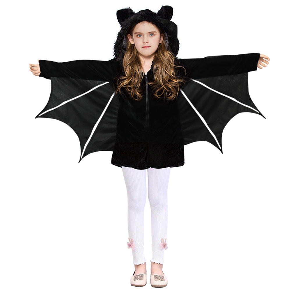 Girl in a bat costume with outstretched wings and hood, wearing white leggings with floral accents and beige shoes, against a plain background.