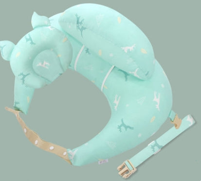 Mint green baby head support pillow with animal and tree patterns on a soft fabric. It features an adjustable tan strap with polka dots and a buckle for secure attachment.