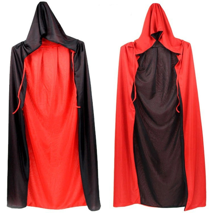 Two reversible hooded capes are displayed. The left cape is black with a red lining, while the right cape is red with a black lining. Both have drawstrings and are made of smooth fabric, showing the contrasting colors when reversed. They hang against a plain white background.