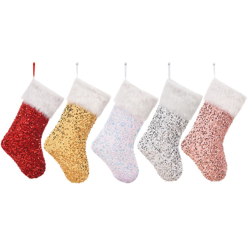 Five glittery Christmas stockings in red, gold, white, silver, and blush pink, each with a white fluffy trim, hanging in a row against a white background.