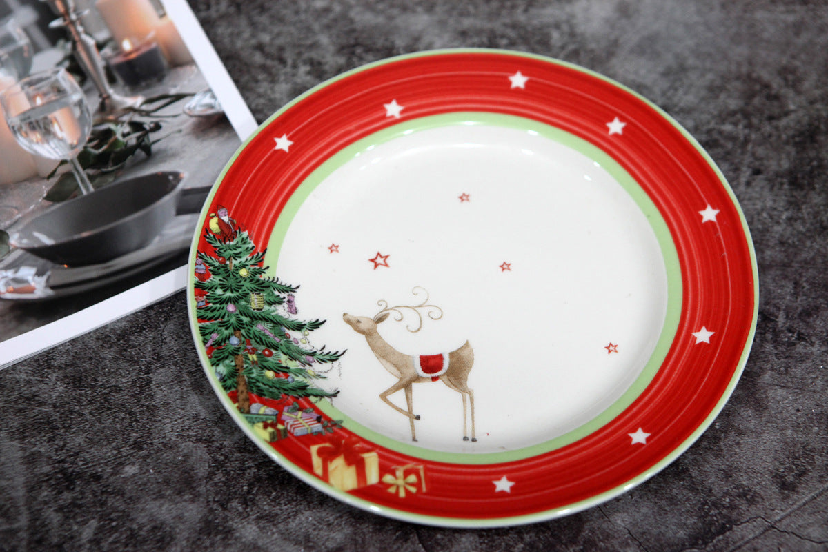 Festive plate featuring a reindeer, Christmas tree, and presents is bordered by a red rim with white stars. Nearby is a photo of an elegant table setting with candles.