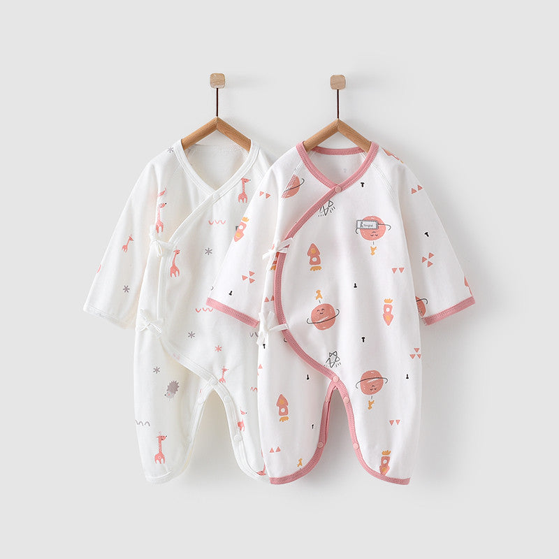 Two baby onesies with playful prints hang on wooden hangers against a white background. One is white with pink and orange animals, the other has space-themed designs with pink trim.