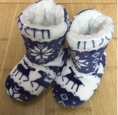 Soft, fleece-lined baby booties with a blue and white winter pattern featuring snowflakes and reindeer, displayed on a wooden surface.