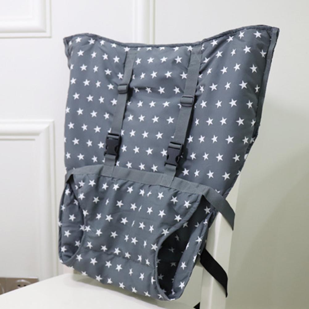 Gray, star-patterned fabric high chair cover with adjustable straps is securely placed on a white chair. Suitable for infant seating and protection.