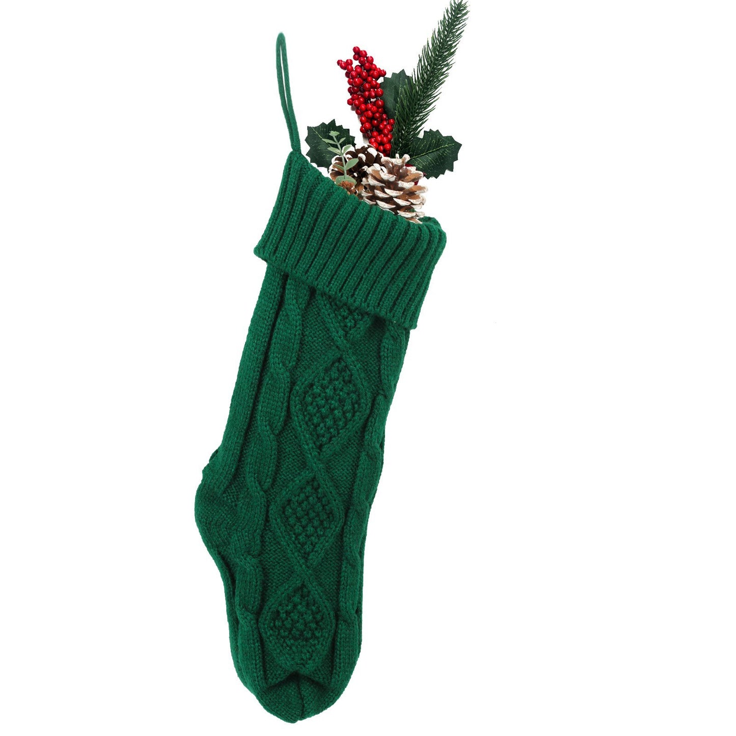 A green knitted Christmas stocking with a diamond pattern, filled with a pine cone, red berries, and evergreen sprigs against a white background.