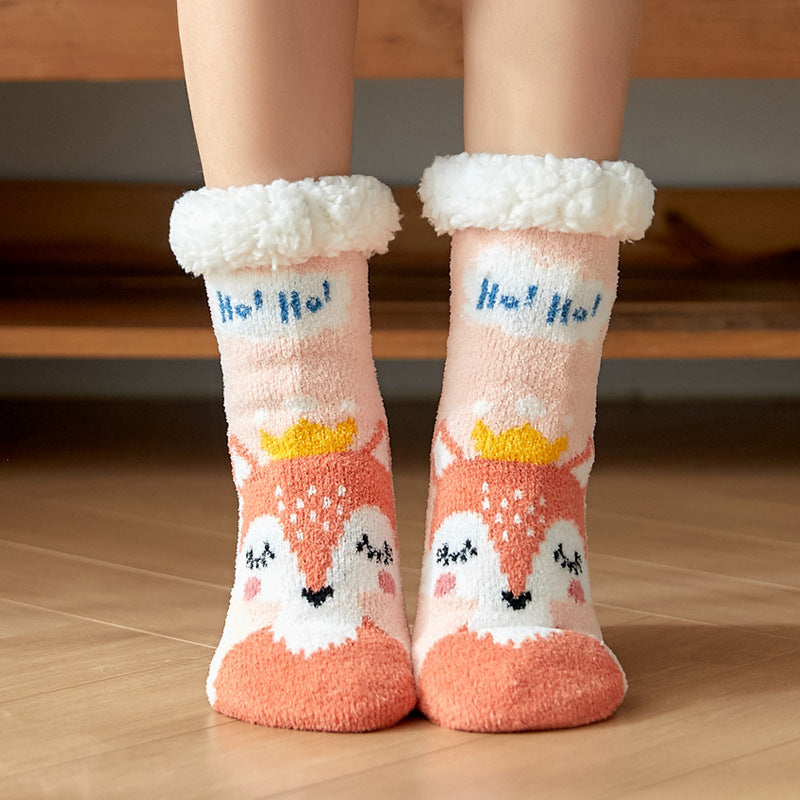 Fluffy cream and peach socks with a cute fox face, wearing a yellow crown, and featuring "Ho! Ho!" text, worn over feet on a wooden floor.