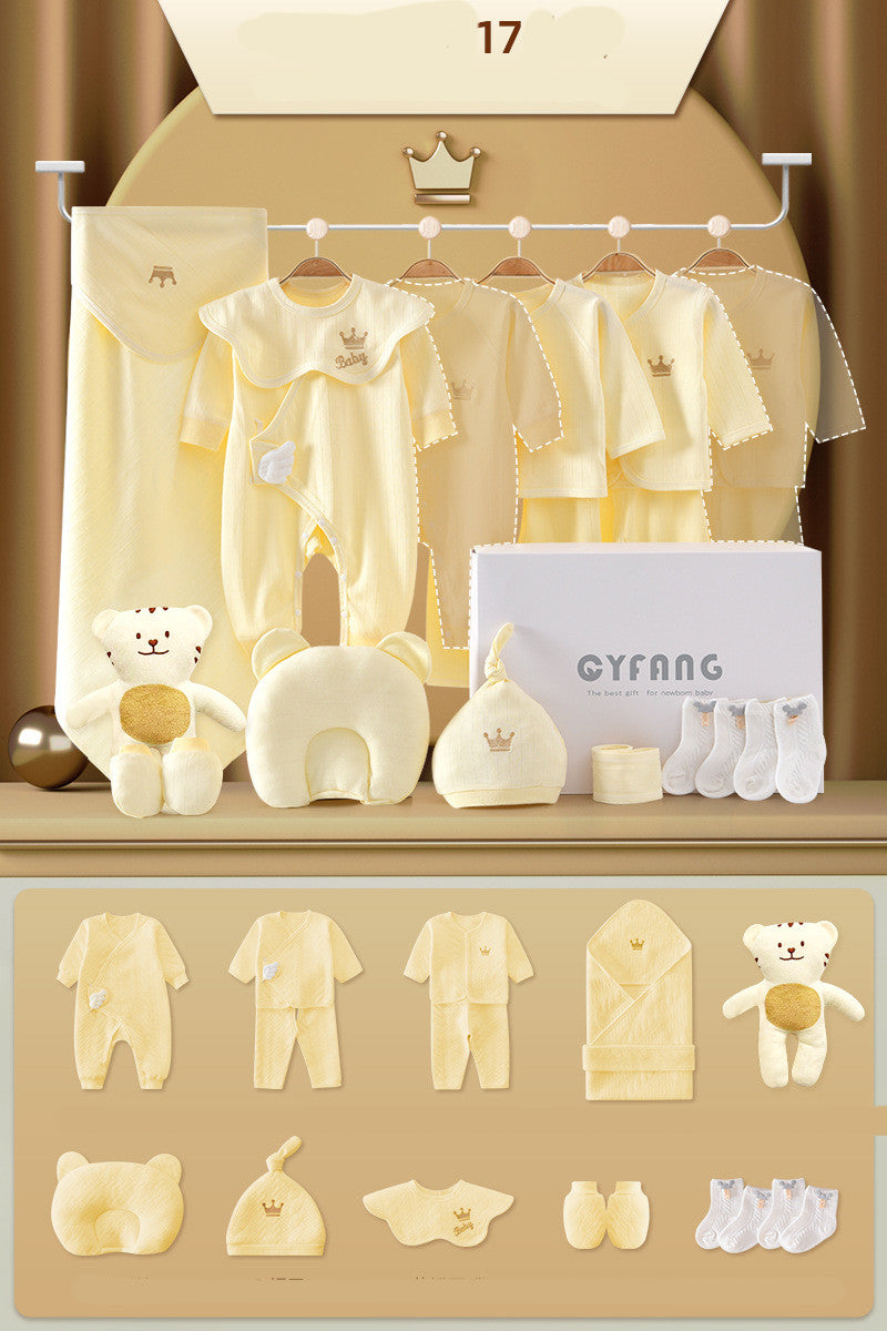 A collection of pastel yellow baby clothing and accessories, including onesies, socks, a hat, a bib, a plush toy, and a gift box, displayed on a shelf against a simple backdrop.