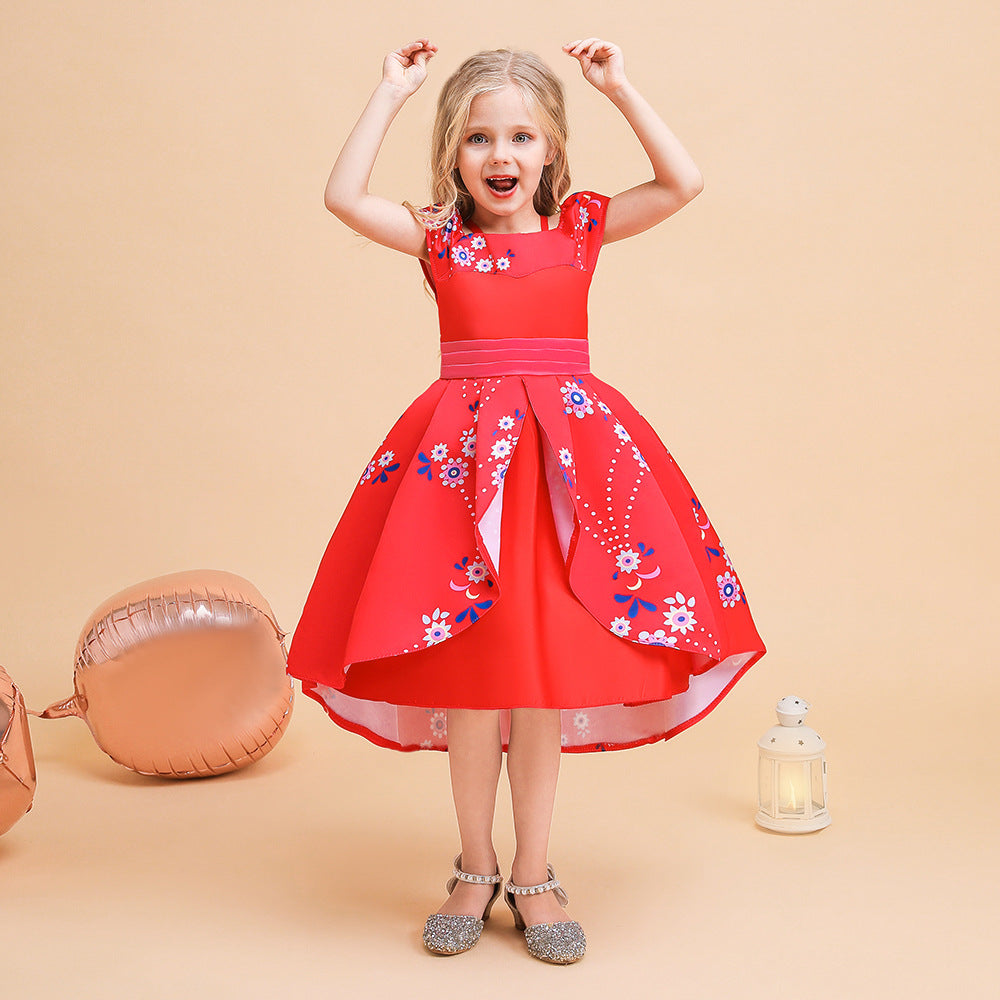 Young girl in a vibrant red dress with floral patterns, arms raised in excitement. She stands on a beige background, with rose gold balloons and a decorative white lantern nearby.