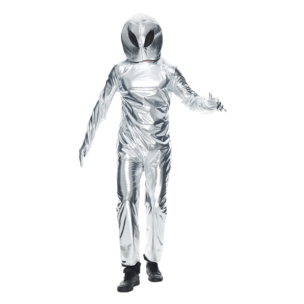 A person dressed in a shiny, metallic silver alien costume with a large, round helmet featuring big, black eyes. The suit covers them from head to toe and appears reflective. The individual is stepping forward with one arm slightly extended, wearing black shoes, against a plain white background.
