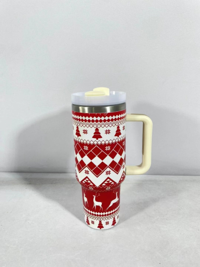Red and white thermos mug with a festive design featuring snowflakes, trees, and reindeer. The mug has a cream handle and lid, and is set against a plain background.