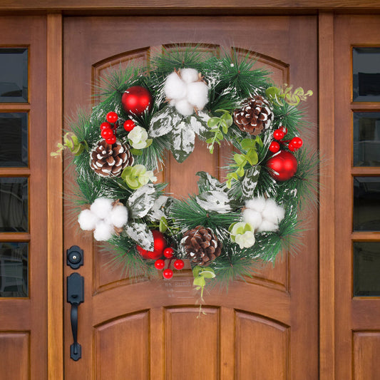 Festive wreath on wooden door, adorned with pinecones, red berries, cotton, red ornaments, and greenery creating a cheerful holiday appearance.