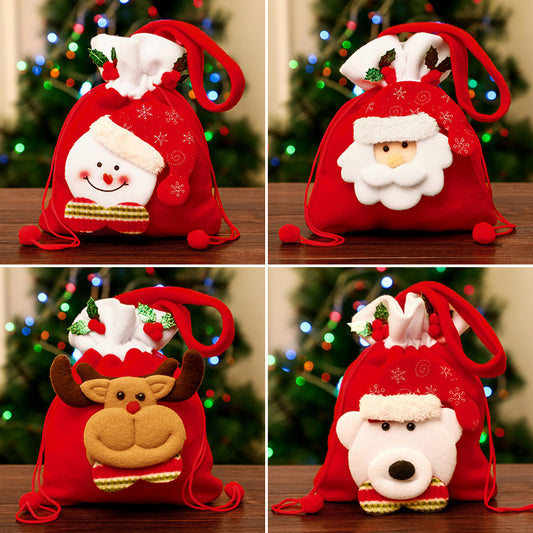 Four red Christmas gift bags with drawstrings, each featuring different festive faces: a snowman, Santa, a reindeer, and a polar bear. A decorated tree is blurred in the background.