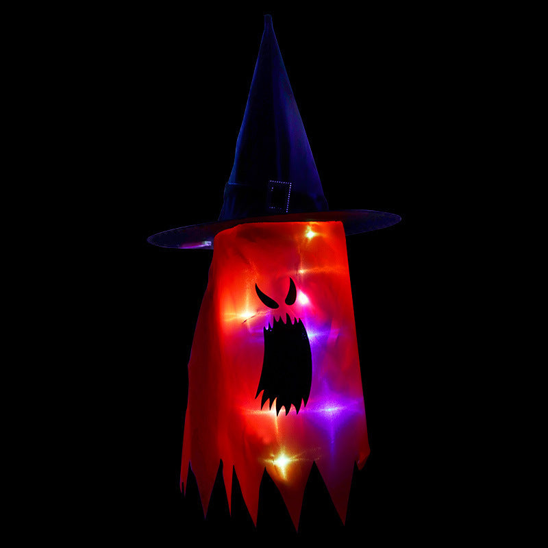 A glowing Halloween ghost decoration illuminated by multicolored lights, wearing a pointed witch hat on a black background, featuring a spooky face with an open mouth and eyes.