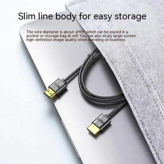 Slim HDMI cable with gold connectors on a laptop, partially covered by a gray felt sleeve. Text highlights its slim 4mm diameter and suitability for easy storage and high-definition display.