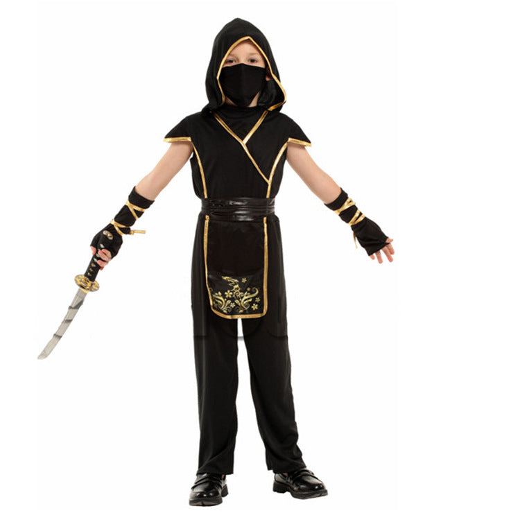 Child in a black ninja costume with gold trim, wearing a hood and mask, holds a curved sword. The costume features floral designs on the front panel.
