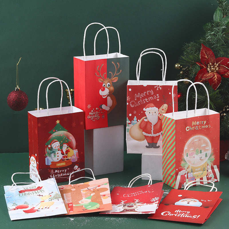 Festive Christmas gift bags with Santa, reindeer, and snowman designs, arranged on a green surface with a red bauble and greenery in the background.