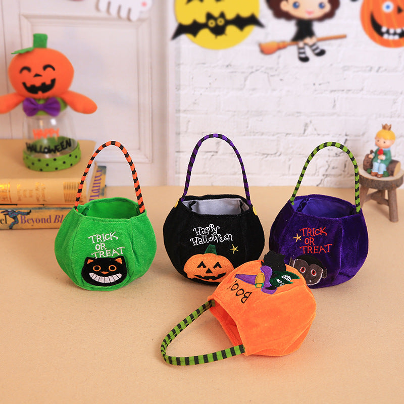 Four colorful Halloween treat bags with festive designs, including pumpkins and black cats. A pumpkin decoration and Halloween-themed wall art are visible in the background.