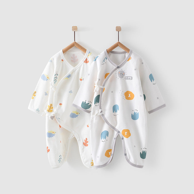 Two baby kimono-style robes with colorful patterns of animals and leaves, hanging on wooden hangers against a light gray background. One robe is mainly white, the other is light gray.