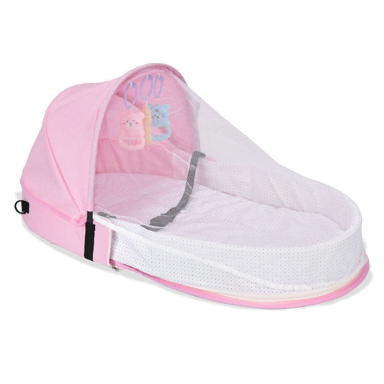 Pink baby bassinet with a canopy and mesh cover, featuring hanging blue and pink teddy bear toys. The interior is lined with white fabric for comfort and safety.