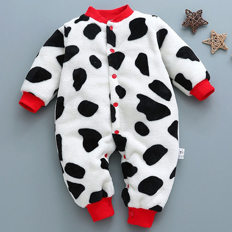 Baby jumpsuit with a cow print pattern, featuring black spots on white fabric. It has red cuffs, collar, and buttons. Two decorative star ornaments are in the background.