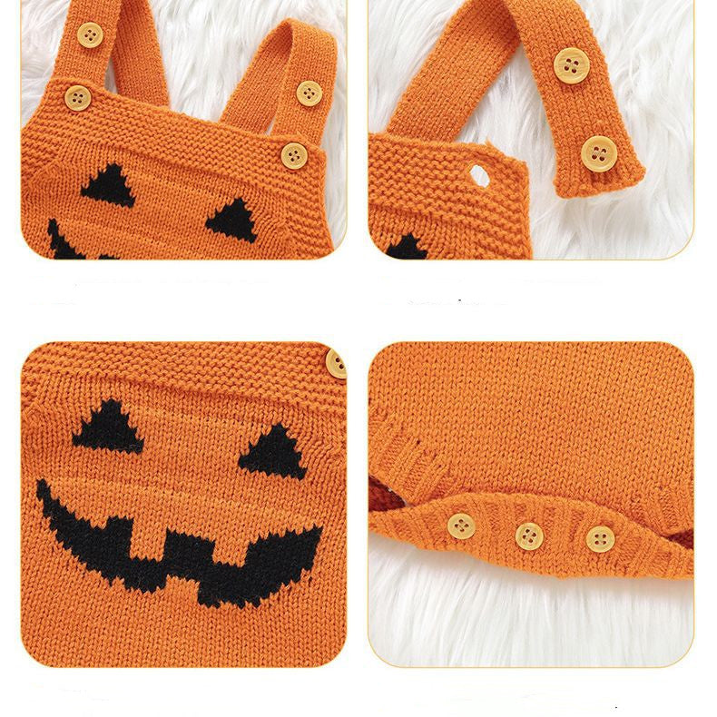Orange knitted romper with black pumpkin face design, featuring buttoned straps and bottom closures, displayed on a soft white background.