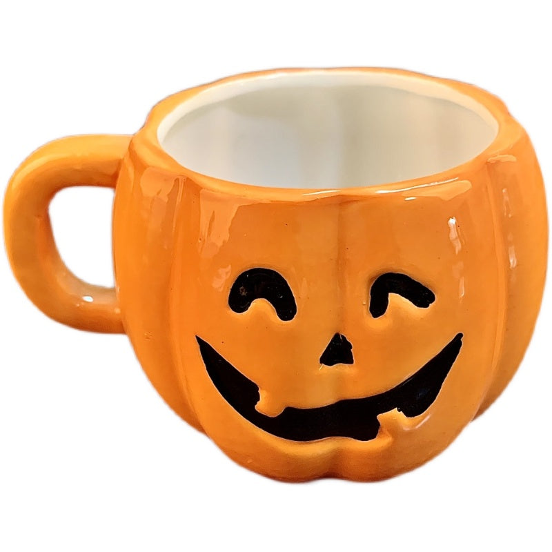 Orange ceramic cup shaped like a pumpkin with a smiling jack-o'-lantern face. The cup features a glossy finish and a handle on one side, mimicking a festive Halloween design.