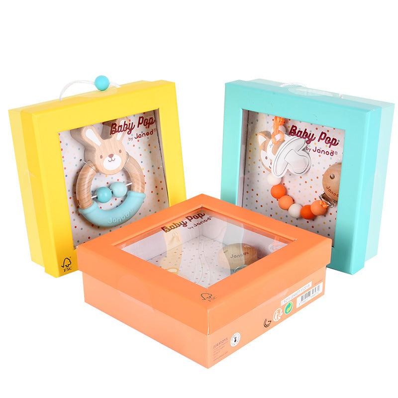 Colorful boxed baby toys, featuring a bunny rattle and beads, displayed in yellow, orange, and blue packaging with the brand "Baby Pop by Janod" on each box.