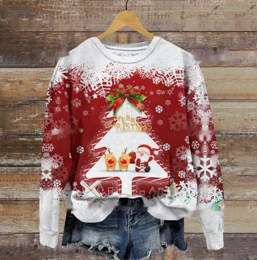 Festive sweater with a red and white Christmas tree design featuring Santa, reindeer, and snowflakes, displayed on a wooden background alongside denim shorts.