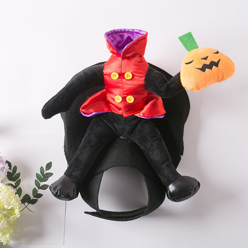 Plush doll with a black body, red satin coat with yellow buttons, and purple lining, holds a smiling pumpkin. Doll is on a white surface with green leaves and flowers nearby.