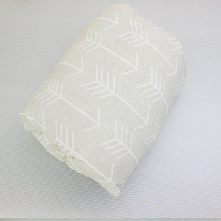 A folded cream-colored fabric with a white arrow pattern, placed on a textured background.
