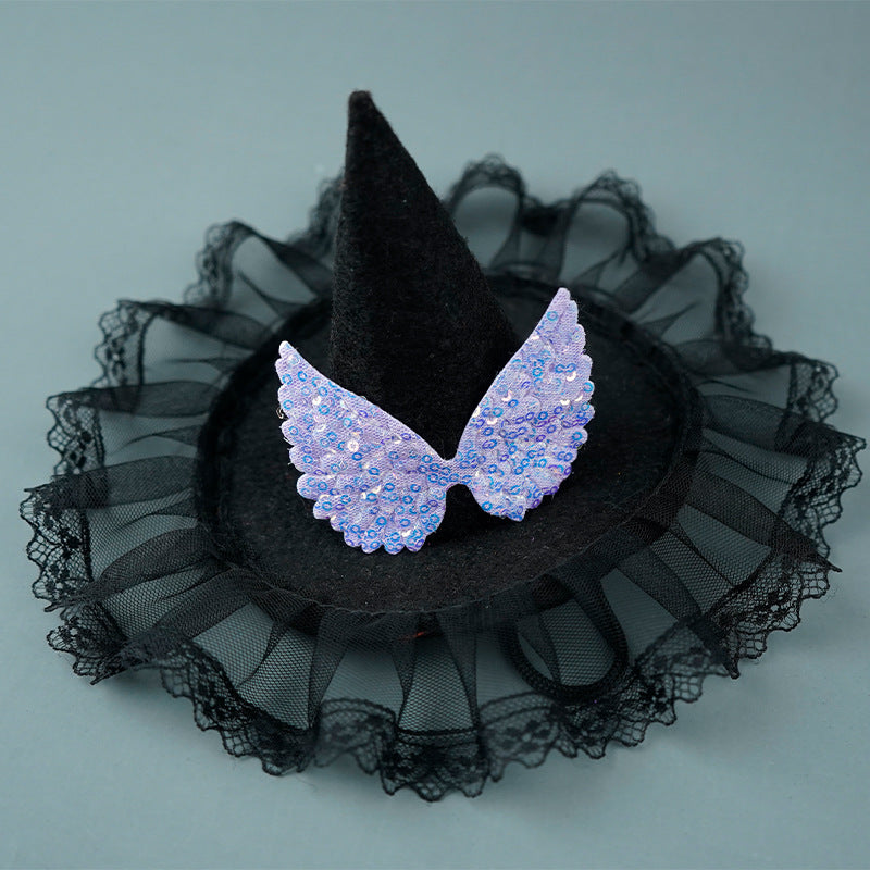 A black witch hat with lace trim features a pair of sparkly lavender sequin wings on the brim, set against a plain gray background.